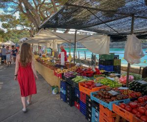Woman in red dress walking through fruit market